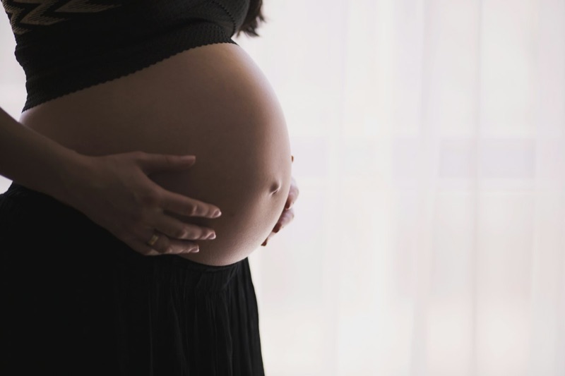 Schwangere Frau hält sanft ihren Bauch